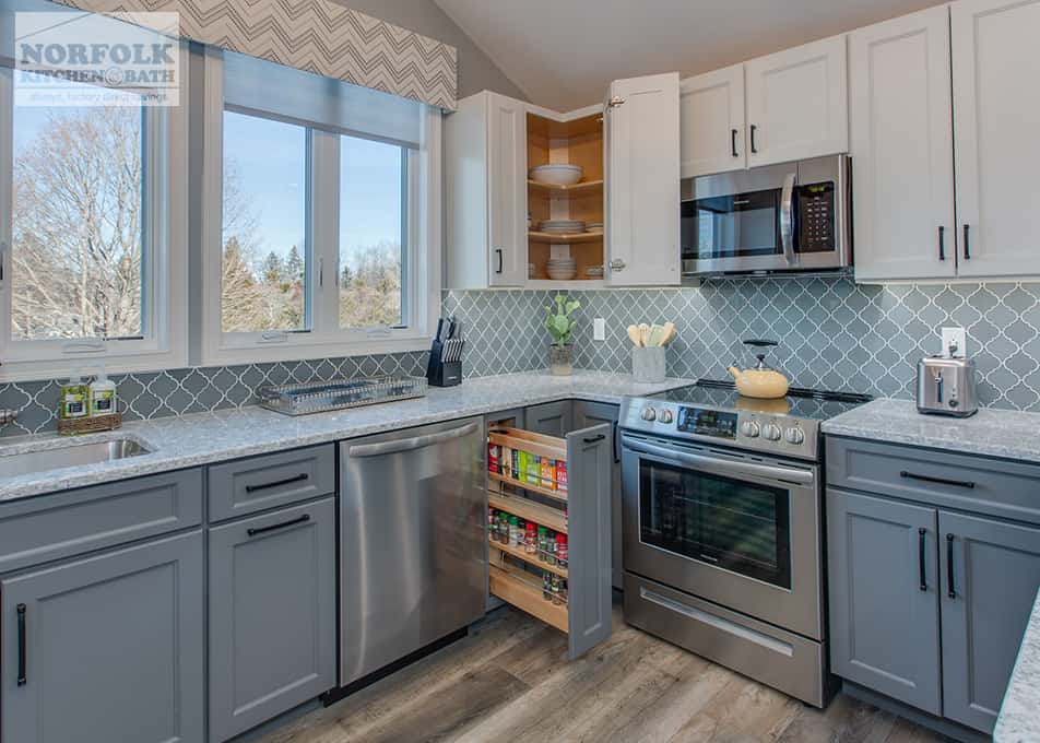 a kitchen remodel in Hampton Falls, NH featuring white and grey kitchen cabinets with a pull out spice drawer and a wall cabinet lazy susan