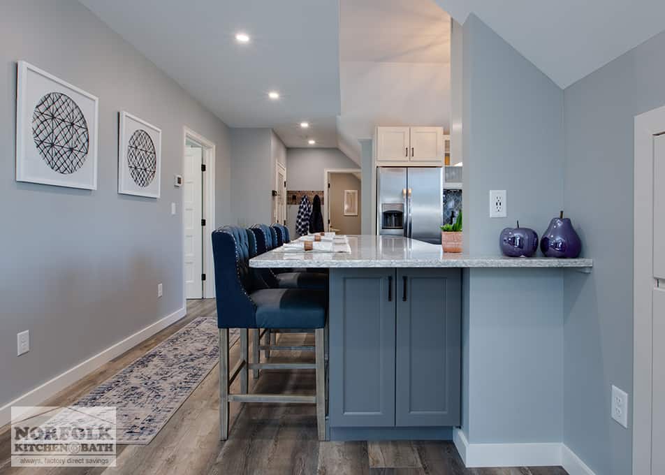 side view of a dark grey kitchen island with a white quartz kitchen countertop and blue bar stools