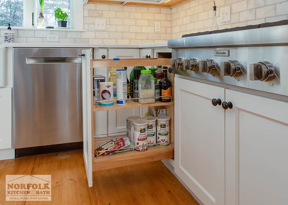 close up of a pull out spice cabinet next to the stove in a white kitchen