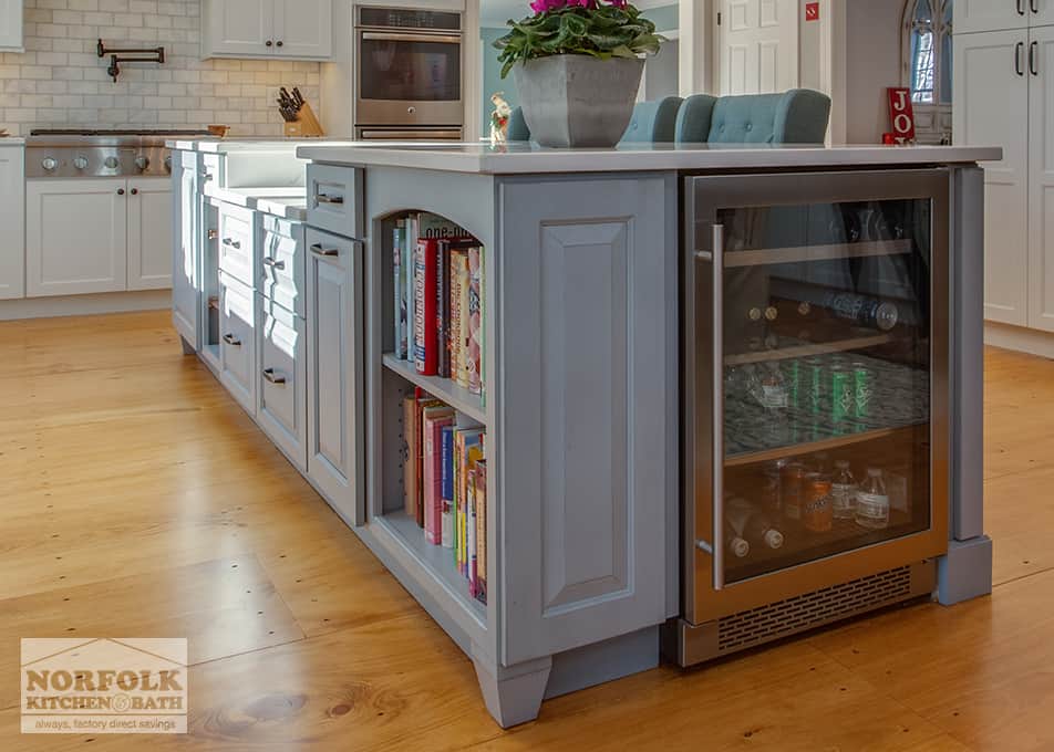 angled view of a gray kitchen island with a built in bookcase and a wine fridge on one end.