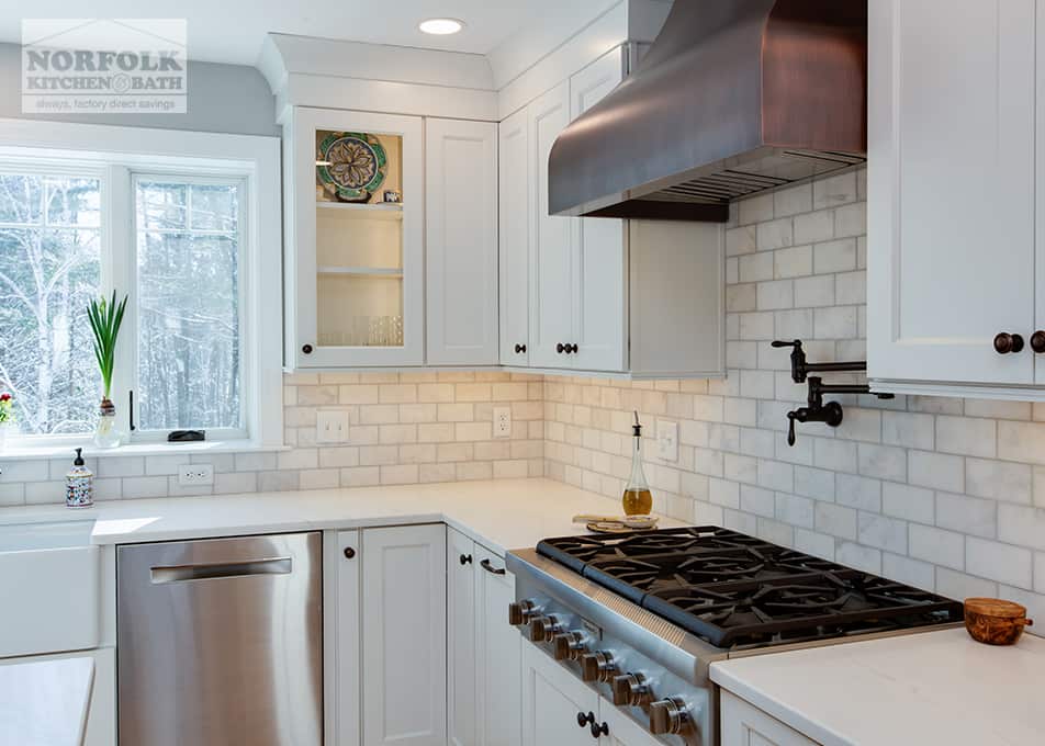 side view of a gas range stove & copper hood in a white kitchen