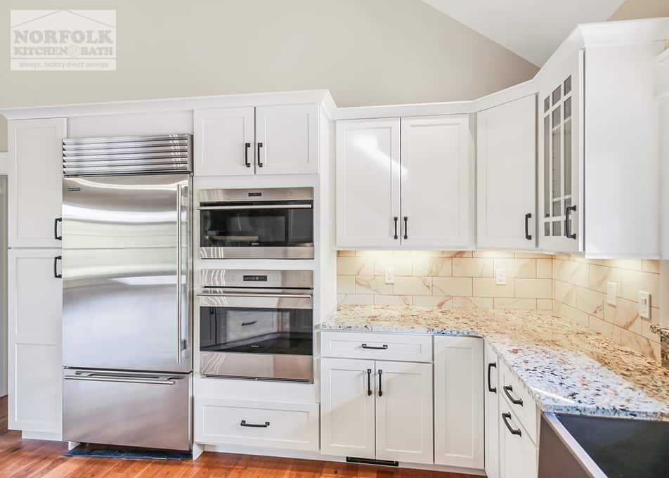 white kitchen cabinets with a stainless steel refrigerator and a wall oven