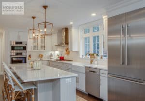 white kitchen with elegant gold finish light fixtures and stainless refrigerator