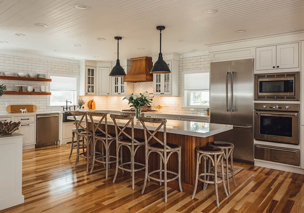 interesting extra large white kitchen with wood color island and stools that look like they were made from tree branches