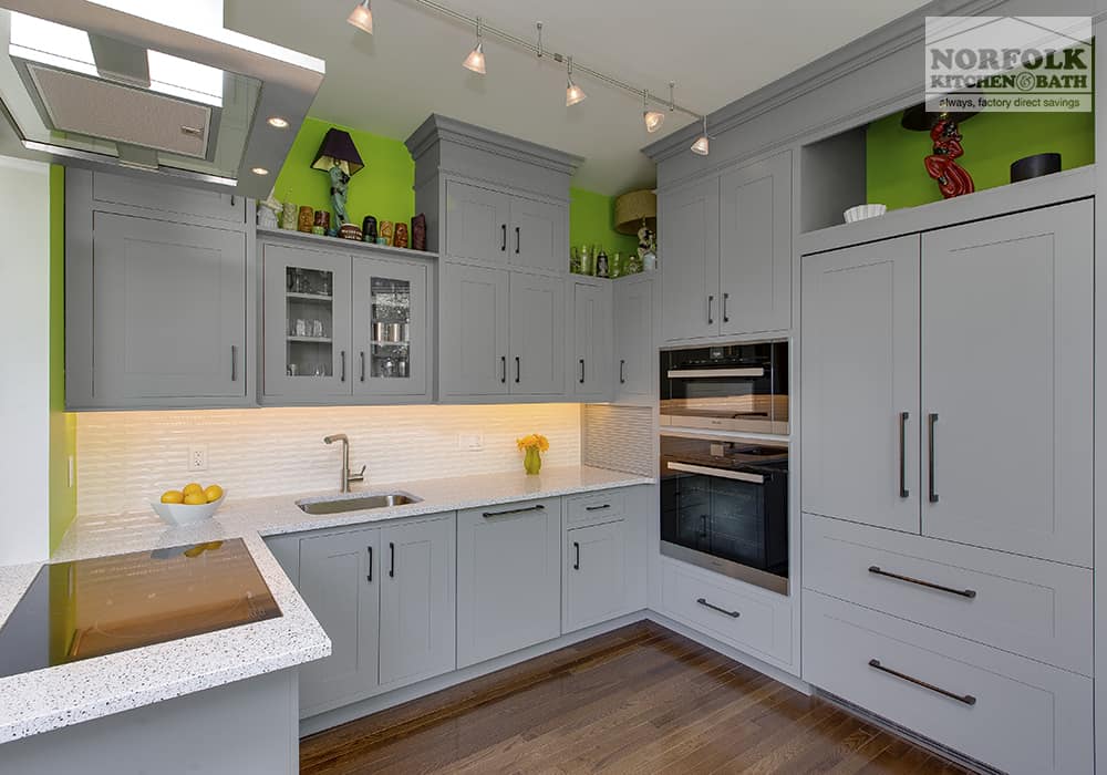 light grey kitchen with bright green paint above wall cabinets and wood floors