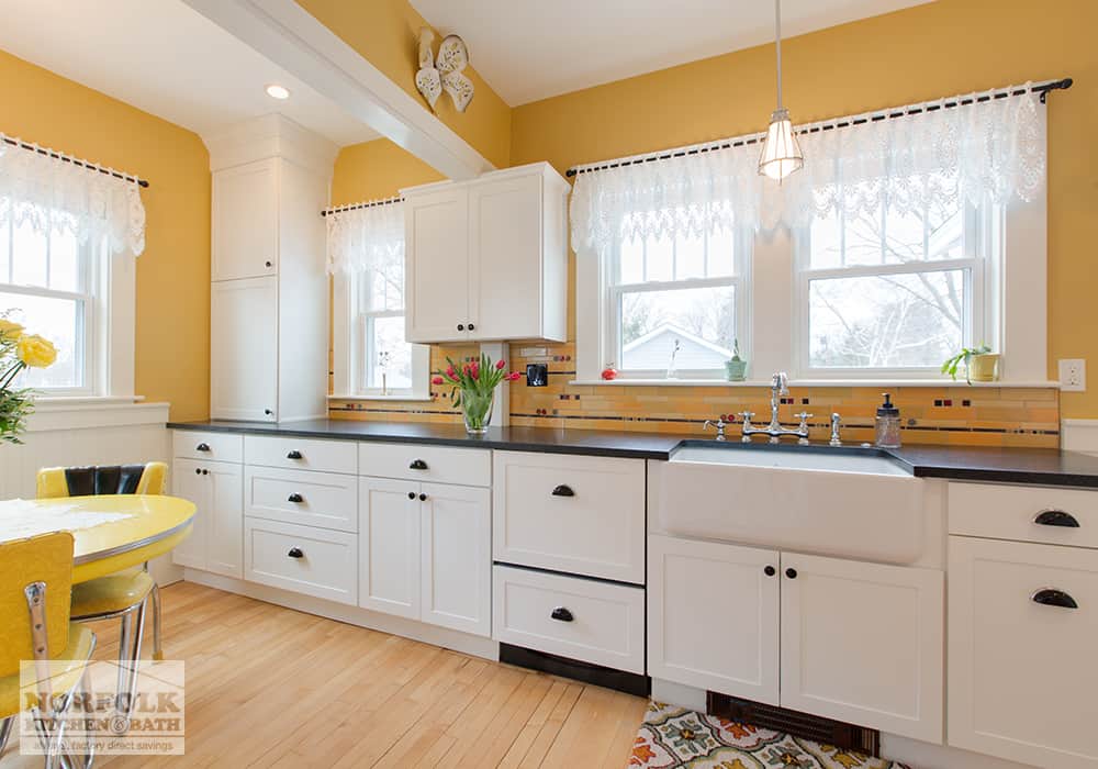 eclectic white kitchen and bright yellow paint and hardwood floors