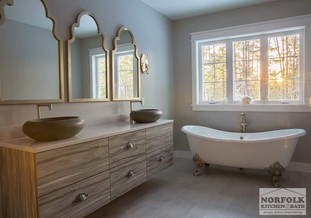 modern master bathroom with claw foot tub and a double vanity with horizontal textured cabinets and bowl sinks sitting on top of the countertop.