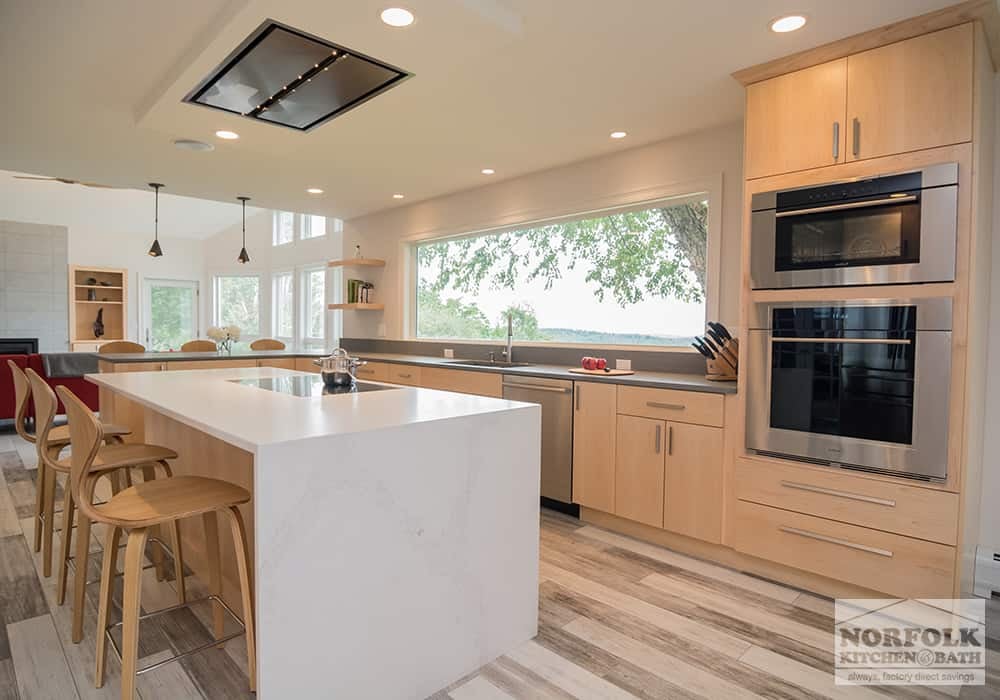 modern kitchen with natural finish cabinets and a large island with a waterfall edge quartz countertop.