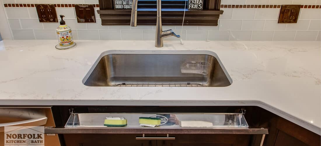 a white countertop and kitchen sink with a tilt-out tray right underneath the sink for storing sponges