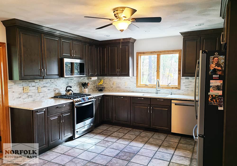 dark brown L-shaped kitchen with quartz and tile flooring