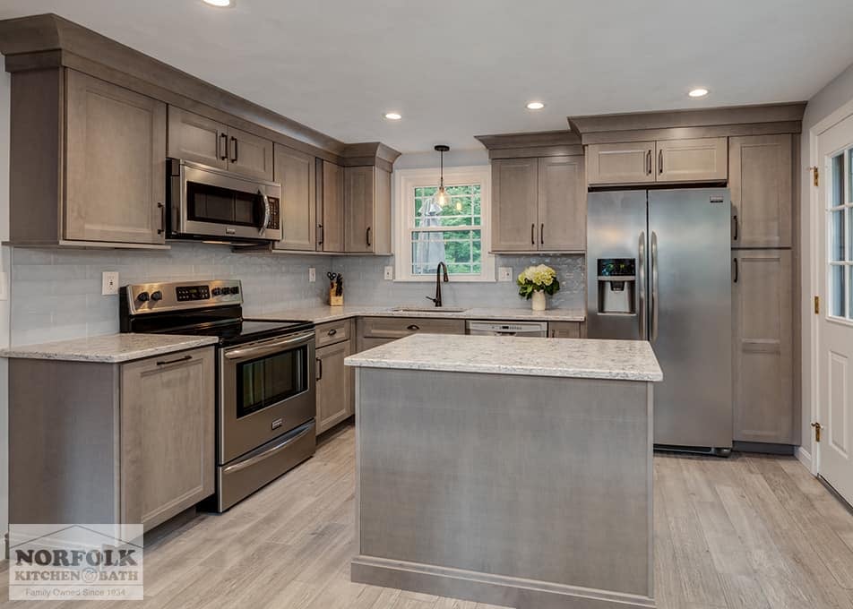a kitchen remodel with shaker cabinets in a gray stain, a small island, white stone countertops and stainless steel appliances