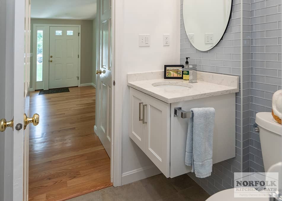 bath remodel in Quincy with a small floating white vanity and oval mirror and a custom tile wall behind