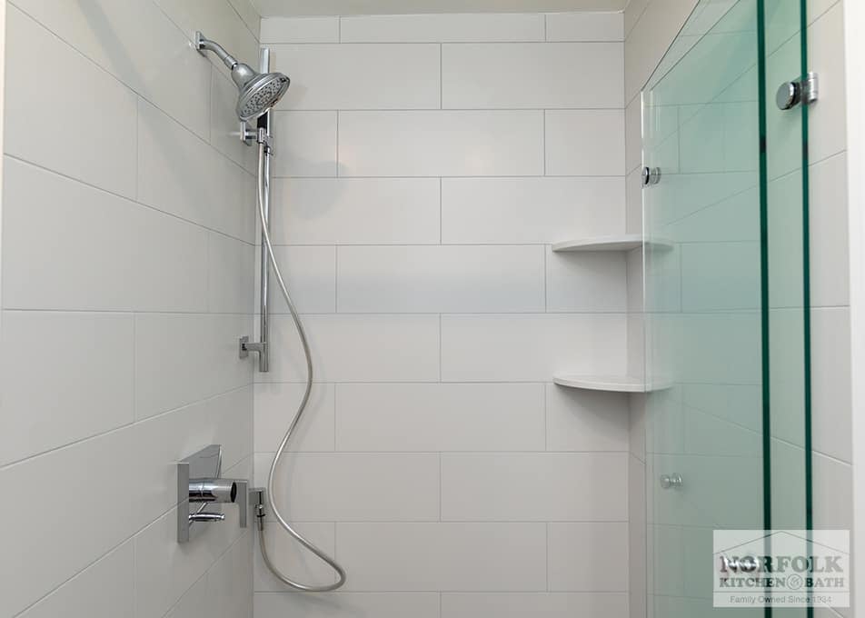 custom shower surround with stainless steel plumbing fixtures and a custom folding glass shower door in Quincy, MA