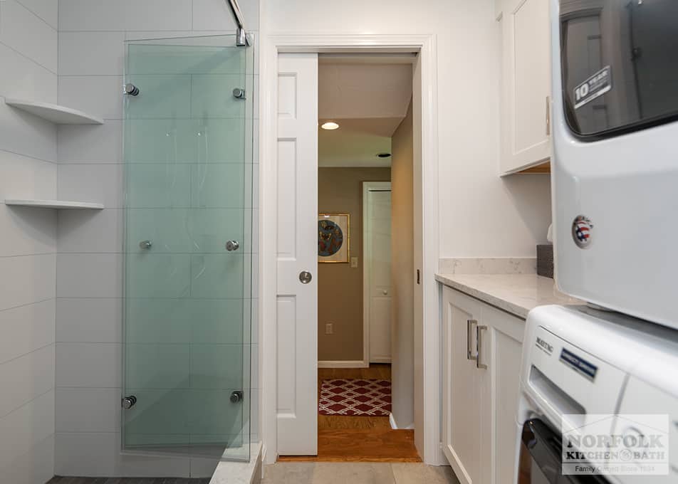 bath and laundry room combo in Quincy with custom folding glass shower door and stacked washer and dryer