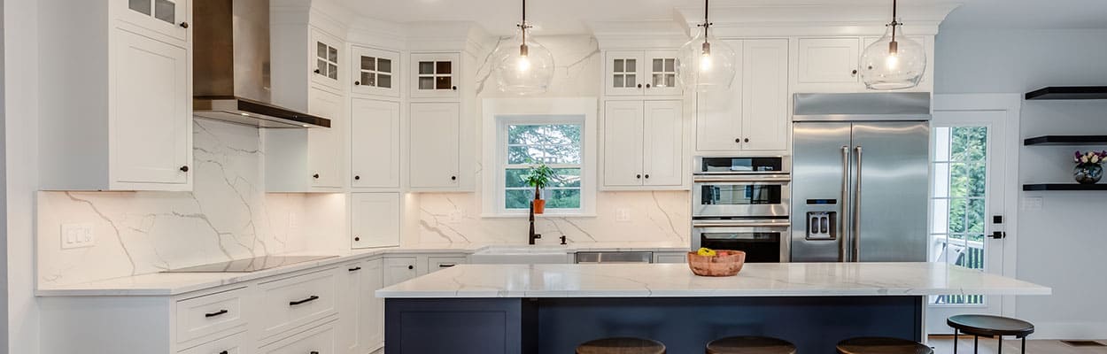 white kitchen cabinets with quartz countertops, a full-height quartz backsplash, and a navy blue accent island with seating