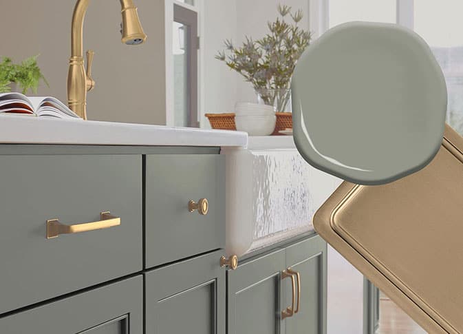 green kitchen cabinets with brushed gold hardware and faucet