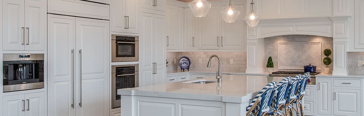 custom kitchen with white cabinets and a large island with blue nautical chairs