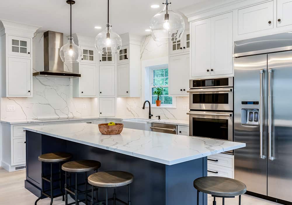 white kitchen cabinets with quartz countertops, a full-height quartz backsplash, and a navy blue accent island with seating